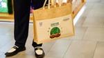 Person holding a reusable tote bag with a “Together for the Planet” design in a store.