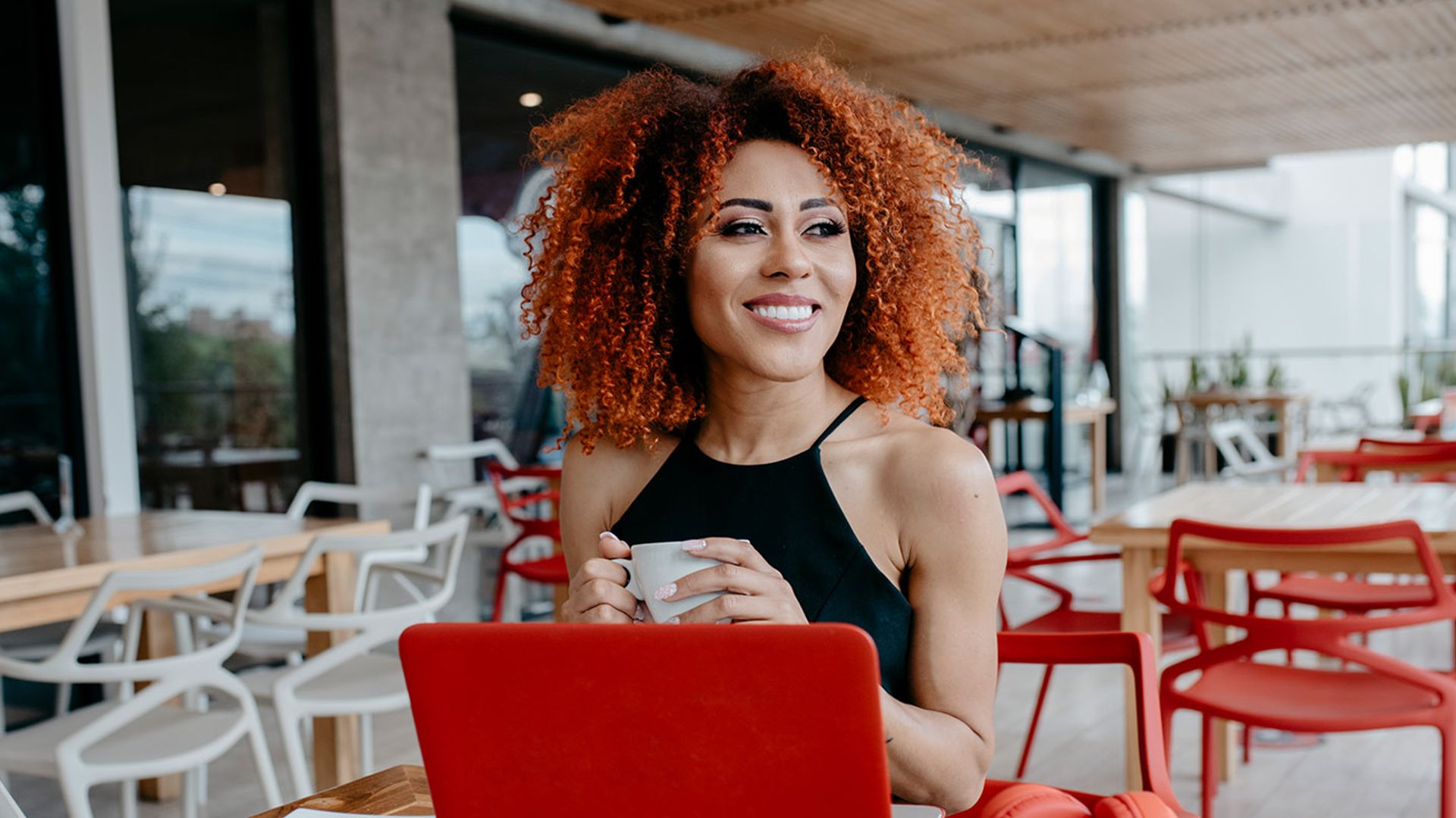 Smiling women with natural curls working on her laptop