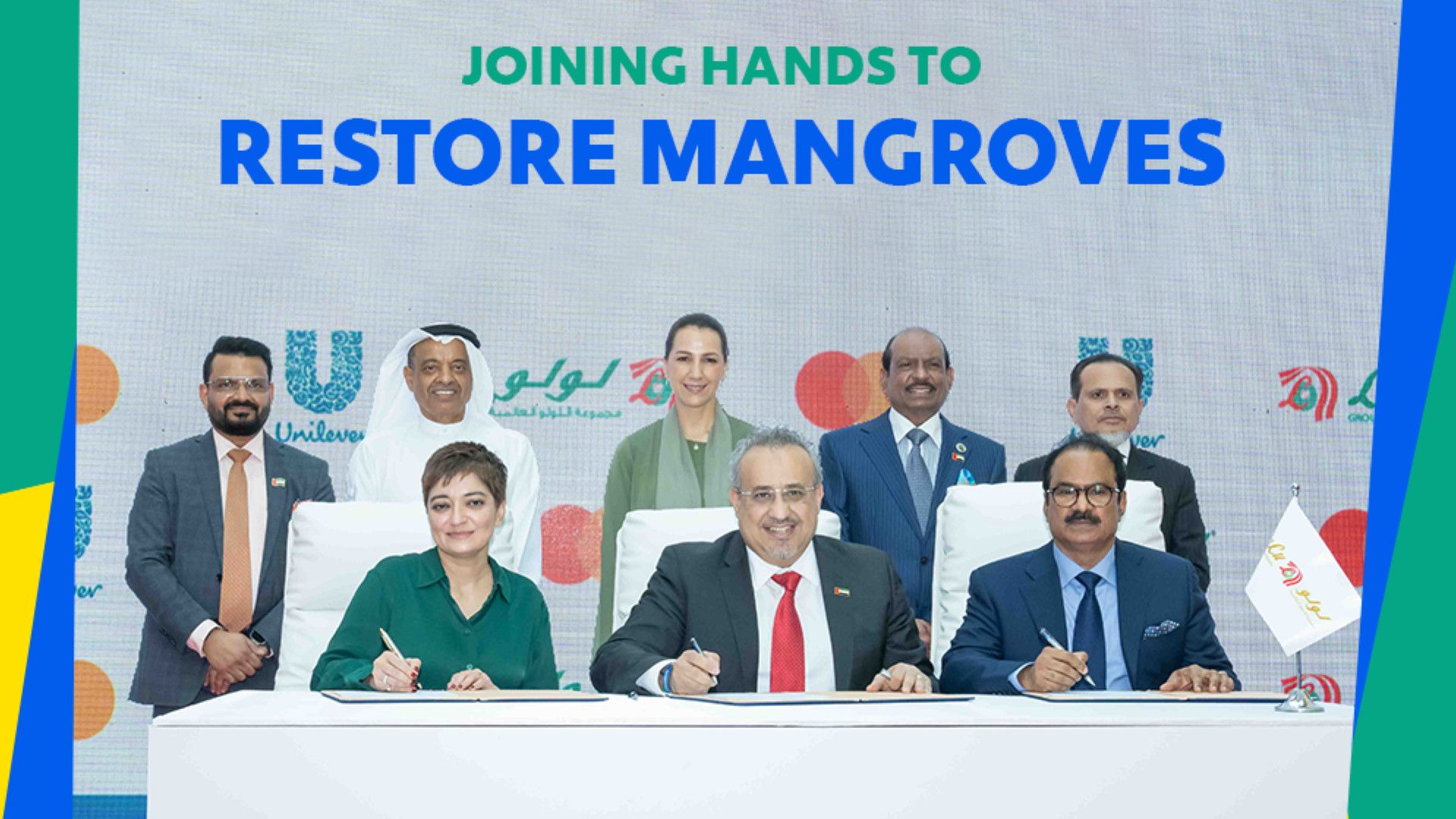 Group of leaders sitting at a table, signing a sustainability focused pledge on restoration of mangroves.