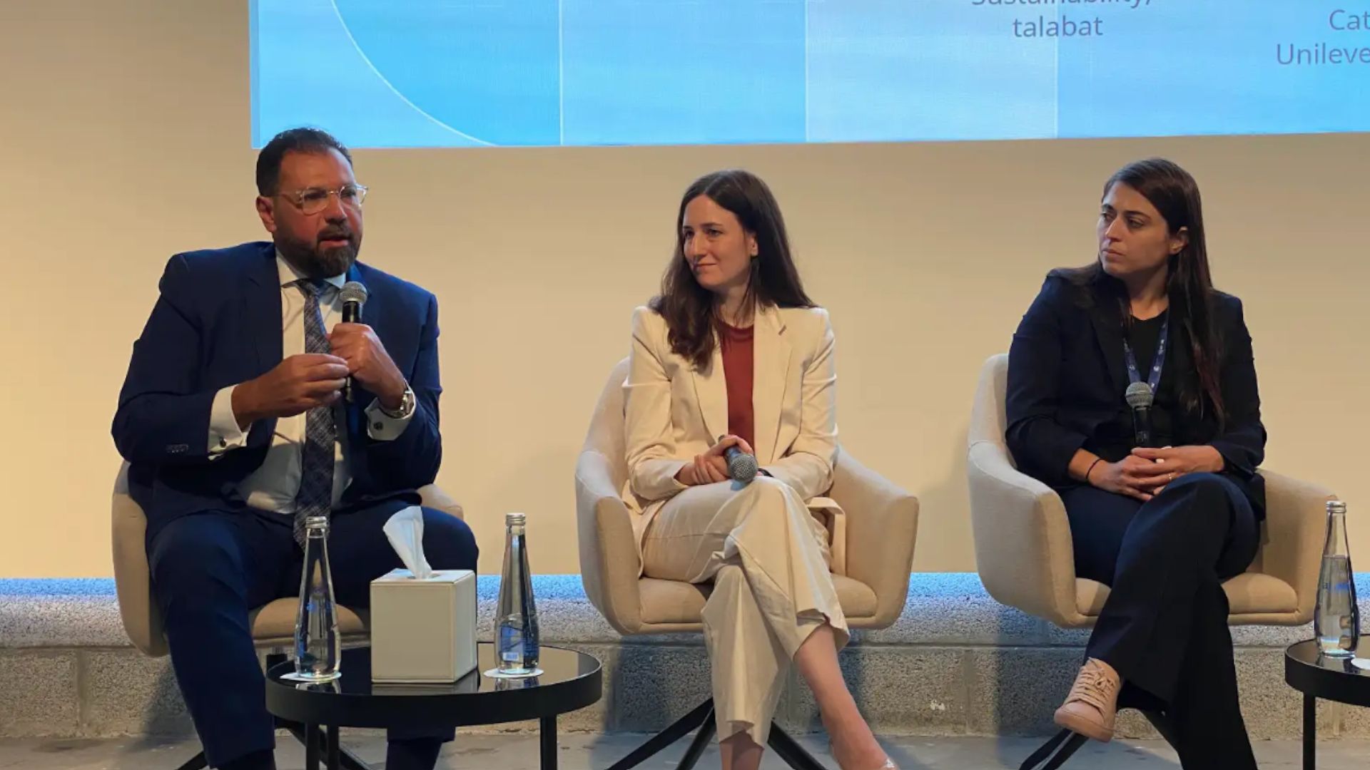 Group of panelists sitting on stage, discussing their pledge to sustainable logistics. 