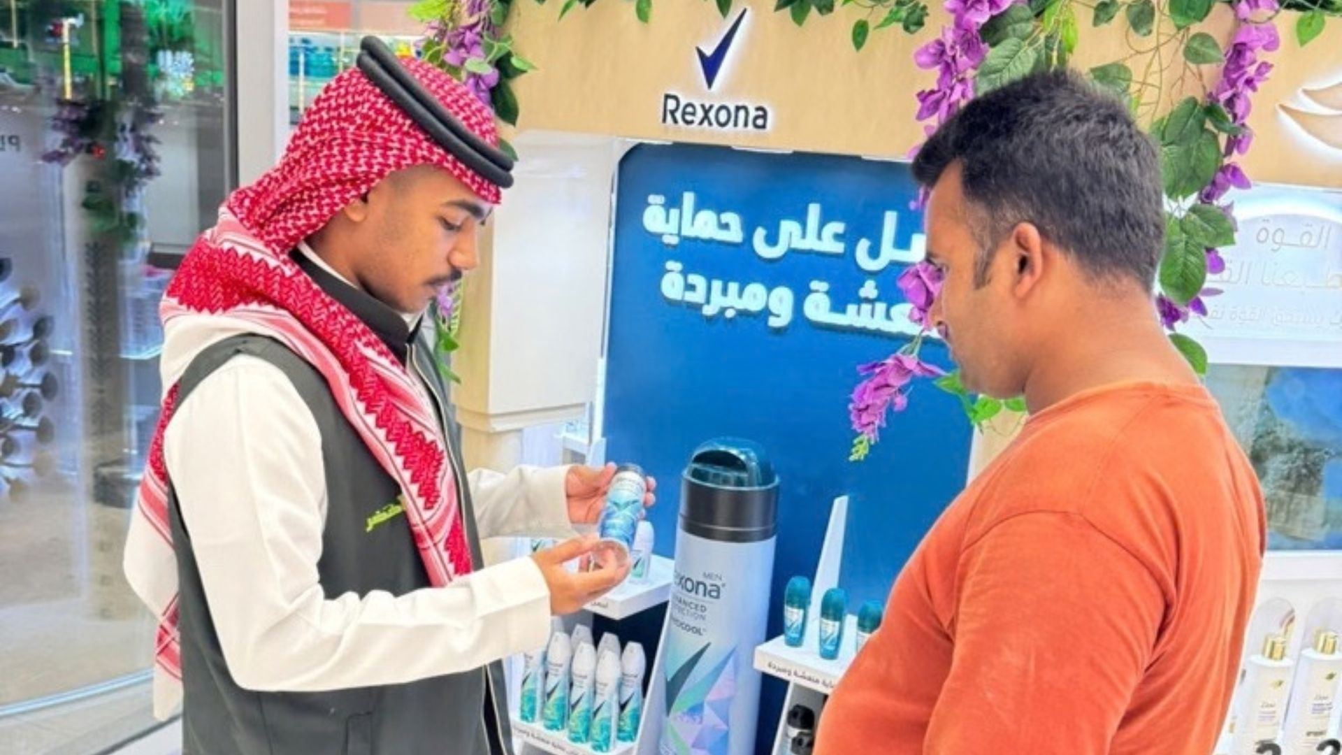 A Rexona representative shows a deodorant product to a customer at a retail display.