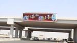 Al-Dawaa pharmacy billboard advertises a buy-one-get-one-free offer above a multilane highway.