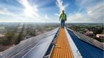 Engineer walking along the roof of a building, checking the maintenance of its energy-producing solar panels